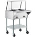 A ServIt stainless steel electric steam table on wheels with an angled glass sneeze guard.