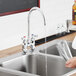 A person pouring water from a Waterloo Blue faucet handle into a glass over a sink.