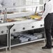 A man standing next to a ServIt electric steam table with food.