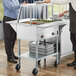 A woman and man standing next to a ServIt steam table with a sneeze guard.