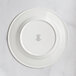 A close-up of a RAK Porcelain ivory wide rim plate with an embossed design.