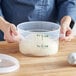 A person holding a Vigor translucent plastic container with white dough inside.