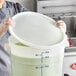 A hand in a glove holding a white Vigor polypropylene lid over a large plastic container.