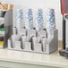 A ServSense countertop cup and lid organizer filled with white cups with blue lines.