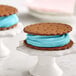 Two ice cream sandwiches with blue frosting on cookies.