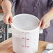 A woman holding a white Vigor polypropylene food storage container lid.