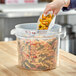 A hand pouring pasta into a Vigor translucent plastic container.