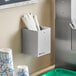 A stainless steel countertop or wall-mount organizer holding wrapped straws.