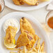 A bowl of fried banana blossom with fries and lemon wedges.