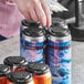 A hand using a black PakTech carrier to pick up a group of cans of beer.