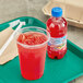 A plastic cup with red Hawaiian Punch on a tray.