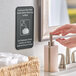 A person using a Tablecraft "Employees Must Wash Hands" sign in a bathroom.