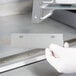 A gloved hand holding a 6" metal grill scraper blade.