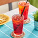 Two glasses of Jarritos strawberry soda with ice on a table on an outdoor patio.
