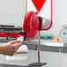 A hand holding a red circular ticket dispenser.
