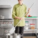 A man in a chef's uniform using a Fourt&#233; stainless steel paddle to stir a pot in a school kitchen.