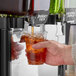 A hand pouring Pure Craft Beverages Berry Tea into a plastic cup.