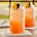 A glass of pink Pure Craft Blackberry Lemonade with orange and lemon slices on a table.