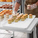 A person in a white apron holding MFG Tray white fiberglass market display tray of food.