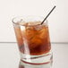 A Libbey rocks glass with a drink and ice on a table.