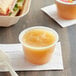 A close-up of a Musselman's Cinnamon Apple Sauce container on a table with a sandwich