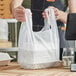 A person holding a white plastic Choice T-shirt bag.