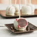 An individually wrapped red velvet cake pop on a stick.