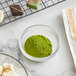 A bowl of Roxy & Rich light green fat dispersible powder next to a plate of chocolates.