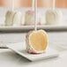 A white plate with individually wrapped white cake pops on it.