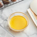 A bowl of yellow liquid next to a tray of chocolates.