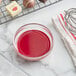 A bowl of red liquid next to a pan.