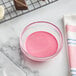 A bowl of pink liquid next to a tray of chocolates.