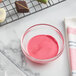 A bowl of pink liquid next to a tray of chocolate squares.