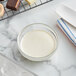 A bowl of white liquid next to a tray of chocolates.