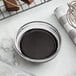 A bowl of liquid chocolate next to a pan of chocolate.
