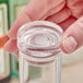 A person using an American Metalcraft cap to hold a glass of clear water.