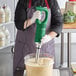 A man using an AvaMix medium-duty immersion blender to mix food in a bowl on a counter.