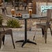 A black powder-coated aluminum outdoor dining table with an umbrella hole, measuring 32 inches by 32 inches.