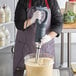 A chef using an AvaMix medium-duty immersion blender on a counter in a professional kitchen.