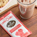 A cup of raspberry hot cocoa and a cookie on a wooden tray.