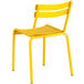 A yellow Lancaster Table & Seating outdoor side chair with metal legs.