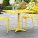 A yellow Lancaster Table & Seating dining table with two chairs on a patio.