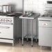 A kitchen with a Regency stainless steel filler table between two stoves and pots.