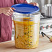 A person holding a blue lid over a large clear food storage container.