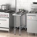 A Regency stainless steel filler table with a backsplash on a counter in a professional kitchen.