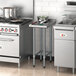 A Regency stainless steel filler table with pots on a counter in a professional kitchen.