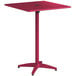 A red Lancaster Table & Seating bar height table with a metal base and a square top with an umbrella hole.