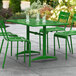 A Lancaster Table & Seating green powder-coated aluminum table with chairs on a patio.