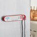 A red and white AvaTemp digital thermometer with a silver magnet.