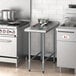 A Regency stainless steel filler table with a backsplash on a counter in a professional kitchen.